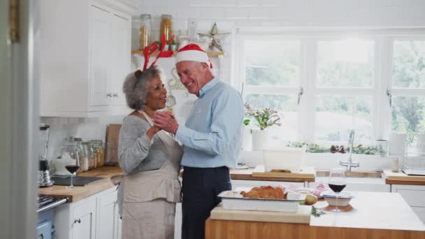 一对年长的夫妇 身穿华丽的连衣裙 头戴驯鹿鹿角 在厨房里跳舞 准备圣诞大餐 动作缓慢 — 图库视频影像