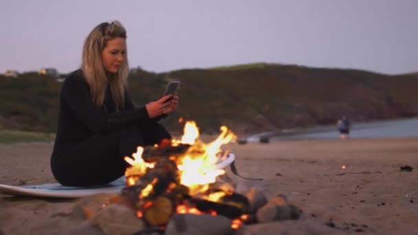 Frau Sommerurlaub Sitzt Mit Handy Lagerfeuer Strand Als Die Sonne — Stockvideo
