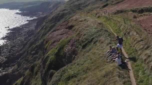 Drone Shot Grupy Przyjaciół Spacerujących Wzdłuż Nadmorskiej Ścieżki Zatrzymując Się — Wideo stockowe