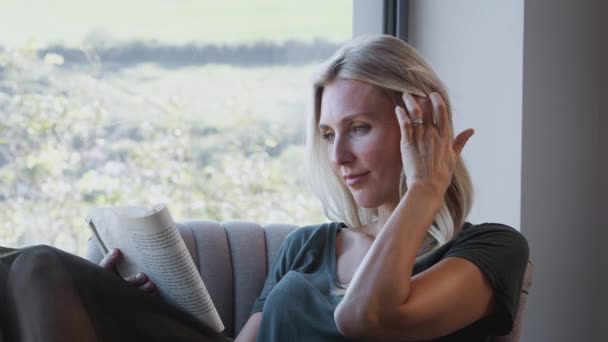 Mujer Relajándose Silla Por Ventana Libro Lectura Casa Disparo Cámara — Vídeo de stock