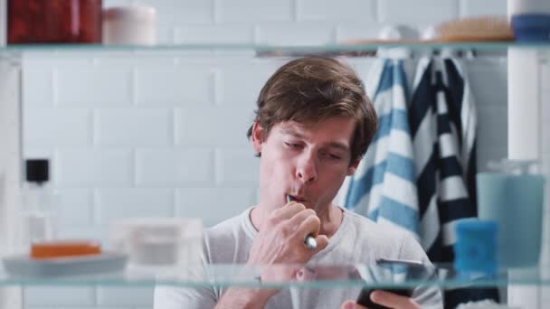 View Bathroom Cabinet Man Brushing Teeth Checking Messages Mobile Phone — Stock Video