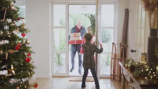 興奮した子供たちは マルチ世代の家族クリスマスを祝うためにプレゼントを持って到着したときに玄関で祖父母を迎える スローモーションで撮影 — ストック動画