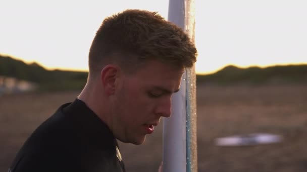 Joven Traje Neopreno Pie Playa Atardecer Sosteniendo Tabla Surf Las — Vídeo de stock