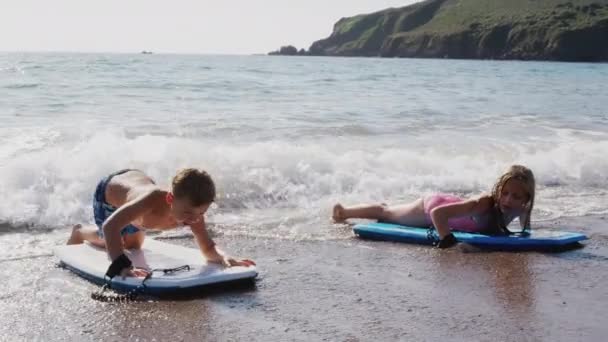 Dwoje Dzieci Bawiących Się Plaży Leżących Deskach Jak Fale Łamią — Wideo stockowe