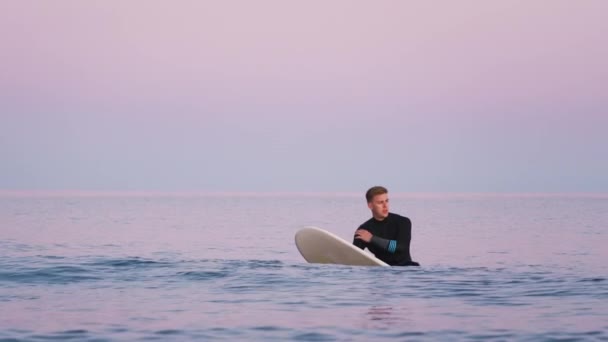 波が彼の周りを破るようにサーフボード上に浮かぶウェットスーツを身に着けている男性サーファー スローモーションで撮影 — ストック動画