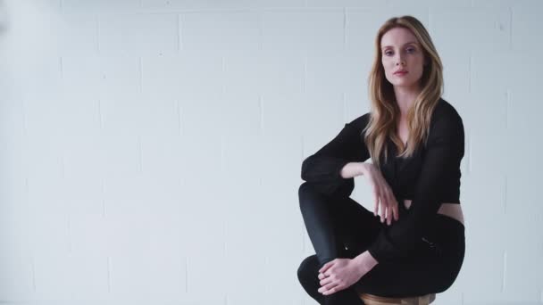 Μόδα Πορτρέτο Της Αυτοπεποίθηση Νεαρή Γυναίκα Κάθεται Κατά Λευκό Τοίχο — Αρχείο Βίντεο