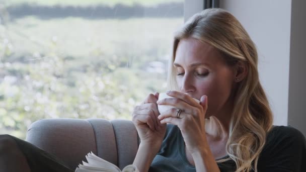 Sıcak Içkisi Olan Kadın Evde Oturup Kitap Okuyor Yavaş Çekimde — Stok video