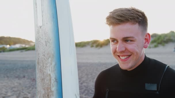 Joven Traje Neopreno Pie Playa Atardecer Sosteniendo Tabla Surf Las — Vídeo de stock