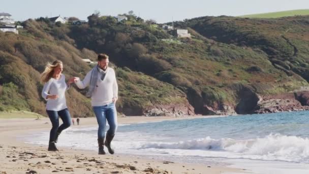 Пара Тримає Руки Бігаючи Вздовж Зимового Пляжу Через Хвилі Разом — стокове відео