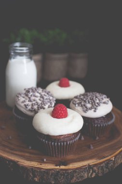 Ahududu ve çikolata çipi cupcakes bir cam şişe süt ile ahşap bir tepside