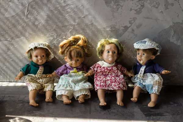 Bonecas velhas, assustadoras, feias na frente da parede de concreto. — Fotografia de Stock