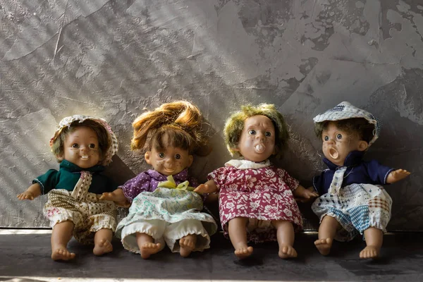 Старі, страшні, потворні ляльки перед бетонною стіною . — стокове фото