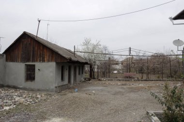 Bahçesinde kuru ağaçlar ve eski gri evleri olan eski bir köy.