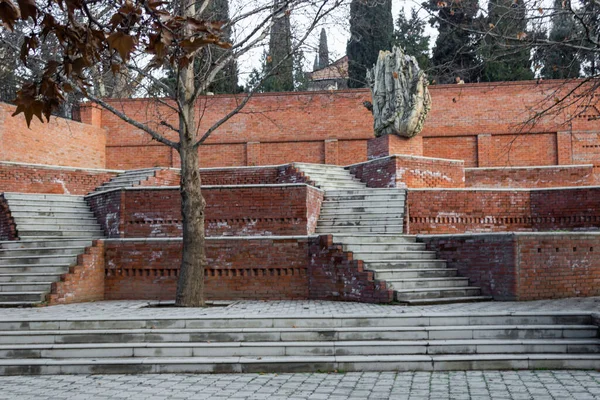 Kırmızı tuğlalı ev ve yeşil ağaçlı ve ilginç binaları olan bir şehir.