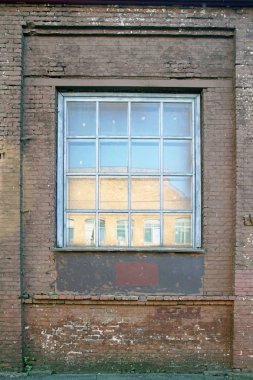    Dikey resim. Tuğla işi ve duvarda bir pencere. Gökyüzü camında yansıma ve karşıdaki bina.                            