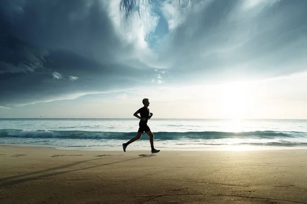 Homme courant sur la plage tropicale au coucher du soleil — Photo