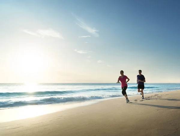 Homem e mulher correndo na praia tropical ao pôr do sol — Fotografia de Stock