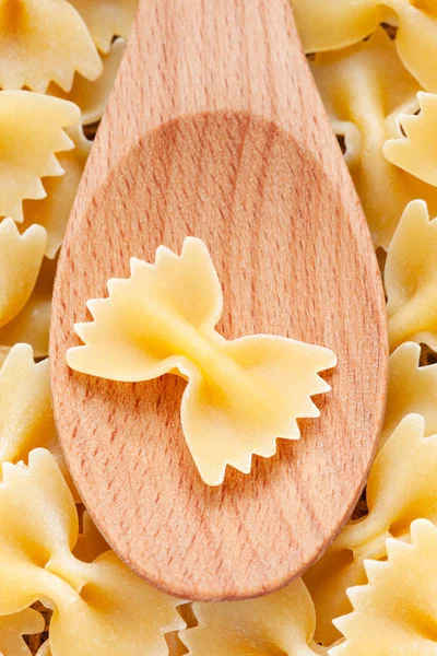 Farfalle pasta in wooden spoon background full frame. — Stock Photo, Image