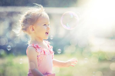Küçük bir kız sabun köpüğü yaz Park yakalar