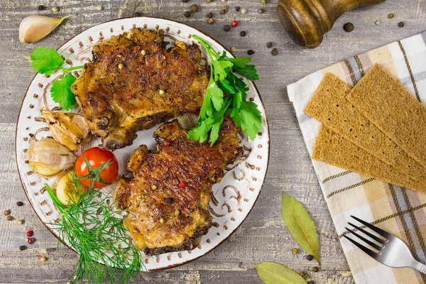 Carne frita em uma chapa com tomates e ervas, pimentas. A comida a mesa de madeira, fundo cinza . — Fotografia de Stock