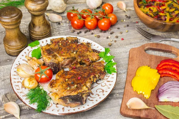 Roasted meat, tomatoes, peppers, onions sliced vegetables on a white dish   cutting Board with  fork and  knife, spices  garlic top view close up  derevna the table. Grey background Royalty Free Stock Photos