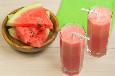 İki cam bardaklar saman hafif ahşap arka plan, lezzetli bir kokteyl, dilim karpuz masaya bir tabak ile karpuz suyu