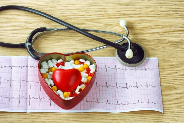 Кардиограмма, стетоскоп, с коробкой таблеток и красным сердцем — стоковое фото