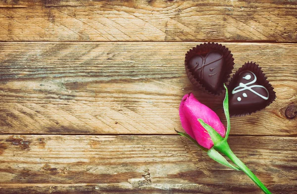 Rosa rosa botão e dois doces de chocolate — Fotografia de Stock