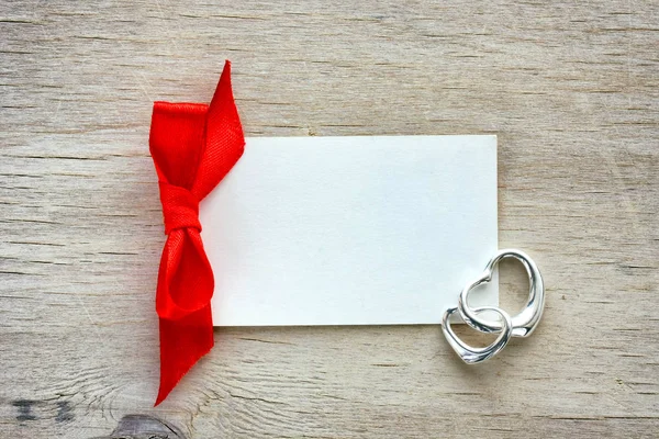 Étiquette vide en papier blanc, ruban rouge, deux coeurs argentés — Photo