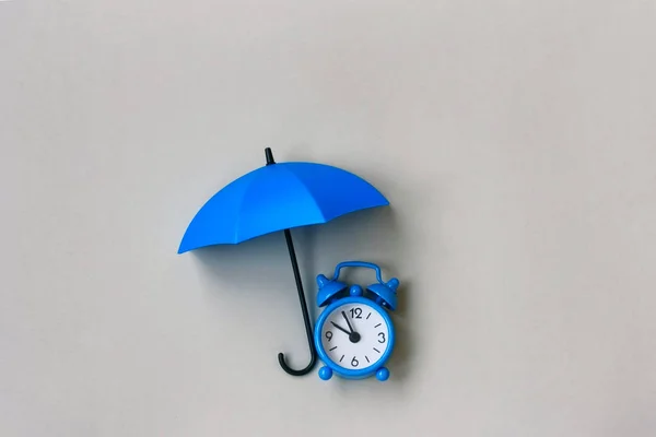 Blue alarm clock under an umbrella — Stock Photo, Image