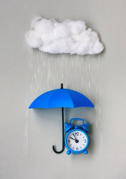 Gri arka plan üzerinde bir şemsiye altında mavi çalar saat — Stok fotoğraf
