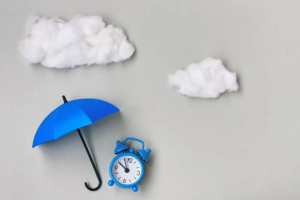 Blue alarm clock under an umbrella on gray background — Stock Photo, Image