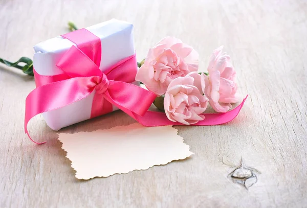 Φόντο ημέρα της μητέρας, κιβώτιο δώρων, τρία ροζ γαρίφαλα, χαρτί — Φωτογραφία Αρχείου
