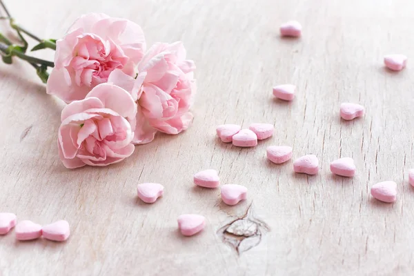 Holiday bakgrunden tre rosa nejlikor, godis hjärtat — Stockfoto