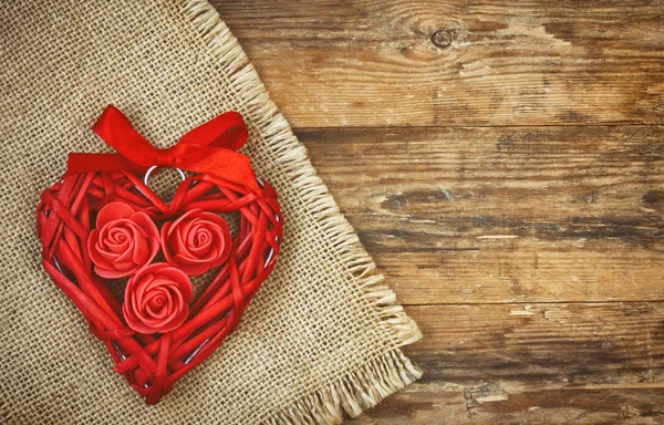 Red wicker heart with roses and ribbon, canvas napkin — Stock Photo, Image