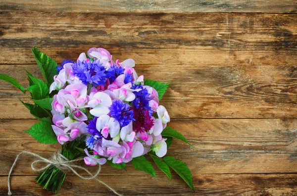 bouquet of cornflowers and sweet peas, on wooden table, vintage