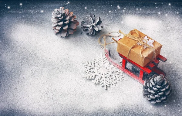 Vánoční přání s červenými saně, dárkové krabice, šišky — Stock fotografie