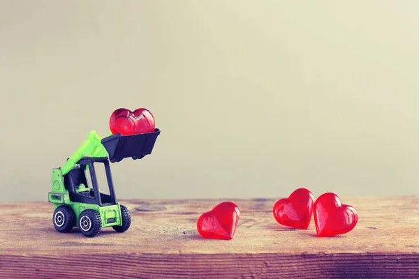 Spielzeugbagger lädt Herz auf Holztisch — Stockfoto