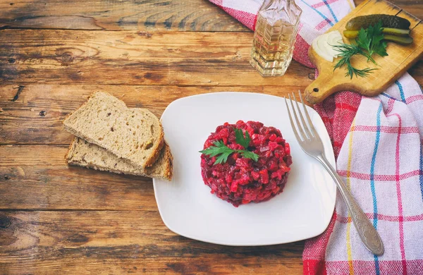 beet salad vinaigrette, in white plate on wooden table, traditional Russian food, boiled vegetables with olive oil, simple meal