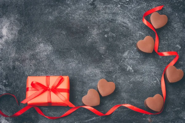 Valentinstag, Schokoladenherz, rote Schleife, Geschenkbox auf Schwarz — Stockfoto