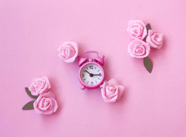 Spring pink background with alarm clock, rose flowers — Stock Photo, Image