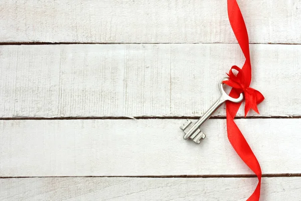 Key with red bow on silk ribbon — Stock Photo, Image