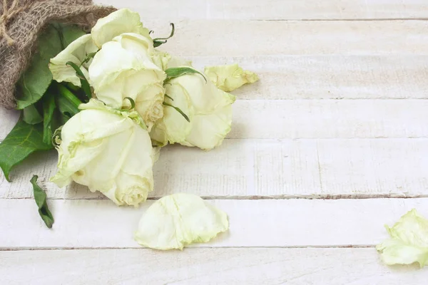 Boeket van witte rozen verpakt in jute verwelkt — Stockfoto