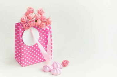 Gül buketli pembe kağıt çanta, bayram hediyesi kartı, şekerleme, beyaz arka plan.