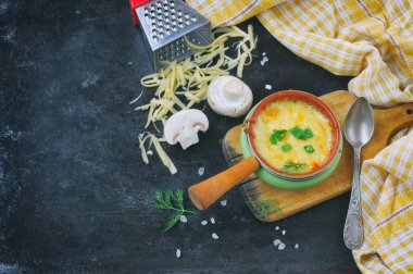 Biri mantarlı fırında jülyen, soğan ve peyniri siyah masada, tahta tahtada, kareli havlu, üst manzara, peynir rendesi