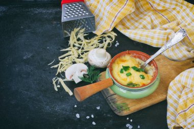 Biri siyah masada, ahşap tahtada, kareli havluda, peynir rendesinde, soğan ve peynirli fırında jülyen servis edecek.