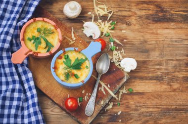 İki porsiyon fırında jülyen, mantarlı, soğanlı ve peynirli ahşap masa.