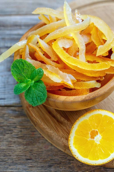 Full bowl of candied orange peel and mint green.