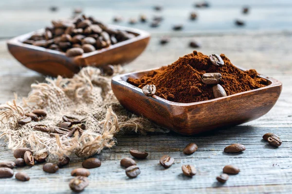 Wooden bowls with ground coffee and coffee beans.