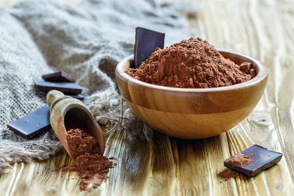 Natural cocoa powder and dark chocolate in a wooden bowl.